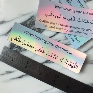 May include: A holographic sticker with the text "When looking into the mirror" and the Arabic phrase "اللَّهُمَّ أَنْتَ حَسَّنْتَ خَلْقِي فَحَسِّنْ خُلُقِي" which translates to "O Allah, just as You have made my external features beautiful, make my character beautiful as well."