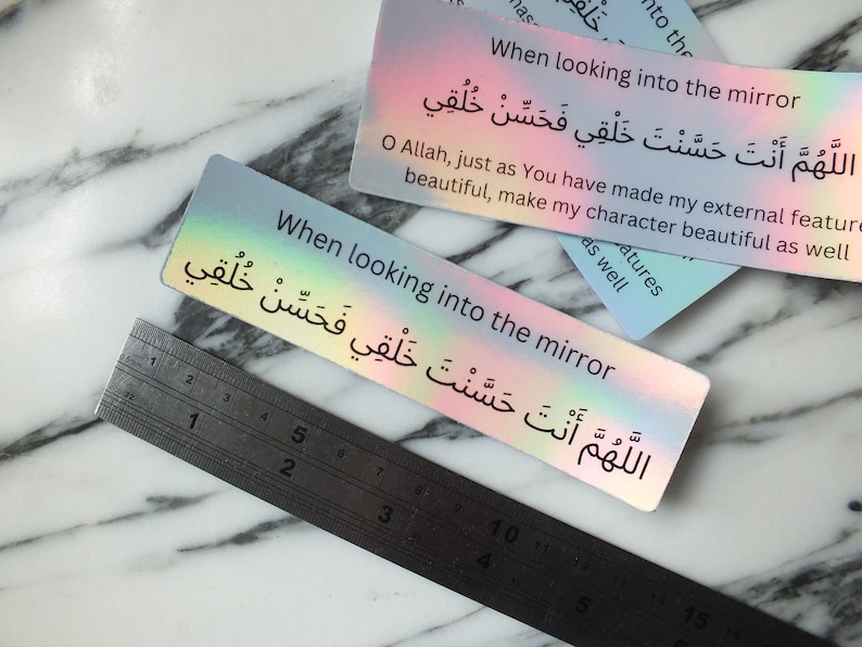 May include: A holographic sticker with the text "When looking into the mirror" and the Arabic phrase "اللَّهُمَّ أَنْتَ حَسَّنْتَ خَلْقِي فَحَسِّنْ خُلُقِي" which translates to "O Allah, just as You have made my external features beautiful, make my character beautiful as well."