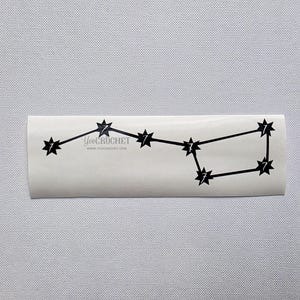 Puede incluir: Una pegatina blanca con un diseño de constelación negra. La pegatina presenta puntos en forma de estrella y el texto "YouCrochet" junto con la dirección del sitio web www.youcrochet.com.