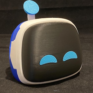 May include: A 3D printed robot toy with a blue and white body, black face, and blue eyes. The robot has a small blue antenna on top of its head.