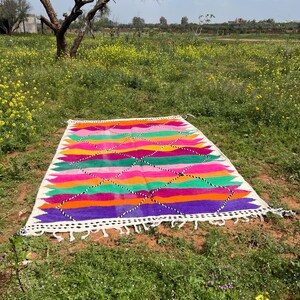 Pode incluir: Uma caneca de cer&acirc;mica branca com uma al&ccedil;a preta e o texto "But First, Coffee" em negrito preto. A caneca est&aacute; sobre um fundo desfocado, sugerindo um ambiente acolhedor.