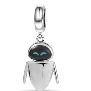 Puede incluir: Un charm de plata con un dise&ntilde;o de robot con cabeza negra y ojos azules. El charm tiene un lazo en la parte superior para sujetarlo a una pulsera o collar. El robot tiene una cabeza redondeada y un cuerpo con lados angulados.