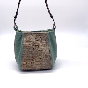 May include: A small, light green leather handbag with a brown strap and a crocodile-embossed panel on the front.