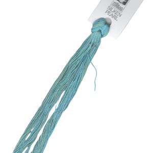 May include: A skein of DMC Silken Pearl embroidery floss in a light blue and green color. The floss is tied in a knot and has a white label attached to it that says "DMC Silken Pearl".