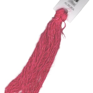 May include: A spool of pink embroidery floss with gold metallic thread. The spool is labeled "Aurora" with a logo of a woman in a dress.