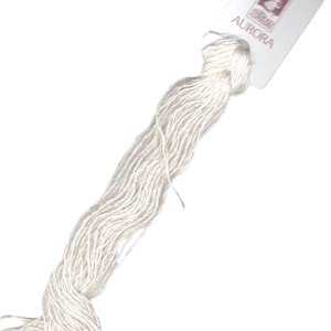 May include: A skein of off-white embroidery floss with a tag that reads "AURORA". The floss is tightly wound and appears soft. The tag has a small illustration and is white with pink text.