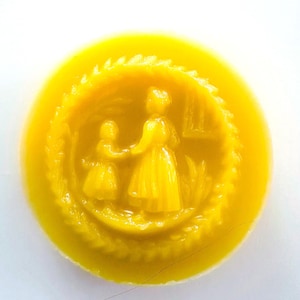 May include: A round, yellow wax seal with a detailed relief of a woman and child holding hands. The figures are surrounded by a textured border, and the overall design is set against a white background.