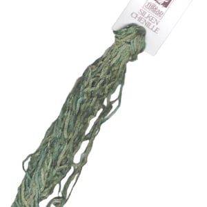 May include: A skein of green and blue silk chenille embroidery floss. The floss is packaged with a white label that reads "The Thread Gatherer Silken Chenille".