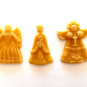 Könnte beinhalten: Drei goldene Engelsfiguren mit filigranen Details. Die Engel tragen Roben und haben Flügel. Sie sind aus einem glatten, glänzenden Material gefertigt.