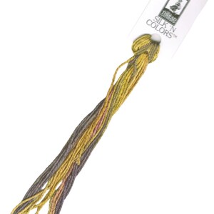 May include: A skein of embroidery floss in shades of brown, yellow, and orange. The floss is labeled "SILK 'N COLORS" and is packaged on a white card.