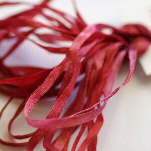 Può includere: Un mazzo di nastro di seta rosso sottile. Il nastro è morbido e delicato, e sarebbe perfetto per aggiungere un tocco di eleganza a qualsiasi progetto.