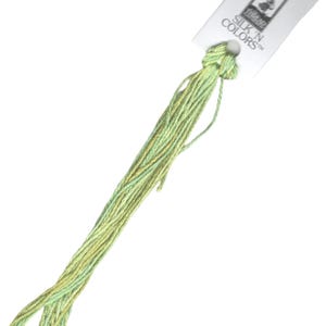 May include: A skein of green and yellow embroidery floss with a white label that reads "Silk 'n Colors".