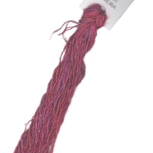 May include: A skein of pink and purple embroidery floss with silver glitter, labeled "AURORA" on a white tag.