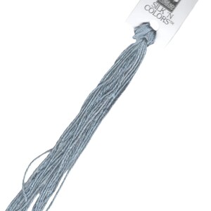Peut inclure: Une pelote de fil à broder en soie bleu clair avec une étiquette blanche sur laquelle est inscrit "SILK 'N COLORS" et qui représente un petit oiseau.