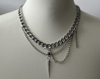 May include: A silver layered chain necklace with a small black bead and a silver spike pendant.