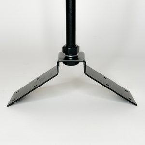 Pode incluir: Base de mastro de bandeira de metal preto com um suporte em forma de V e uma porca redonda no topo.