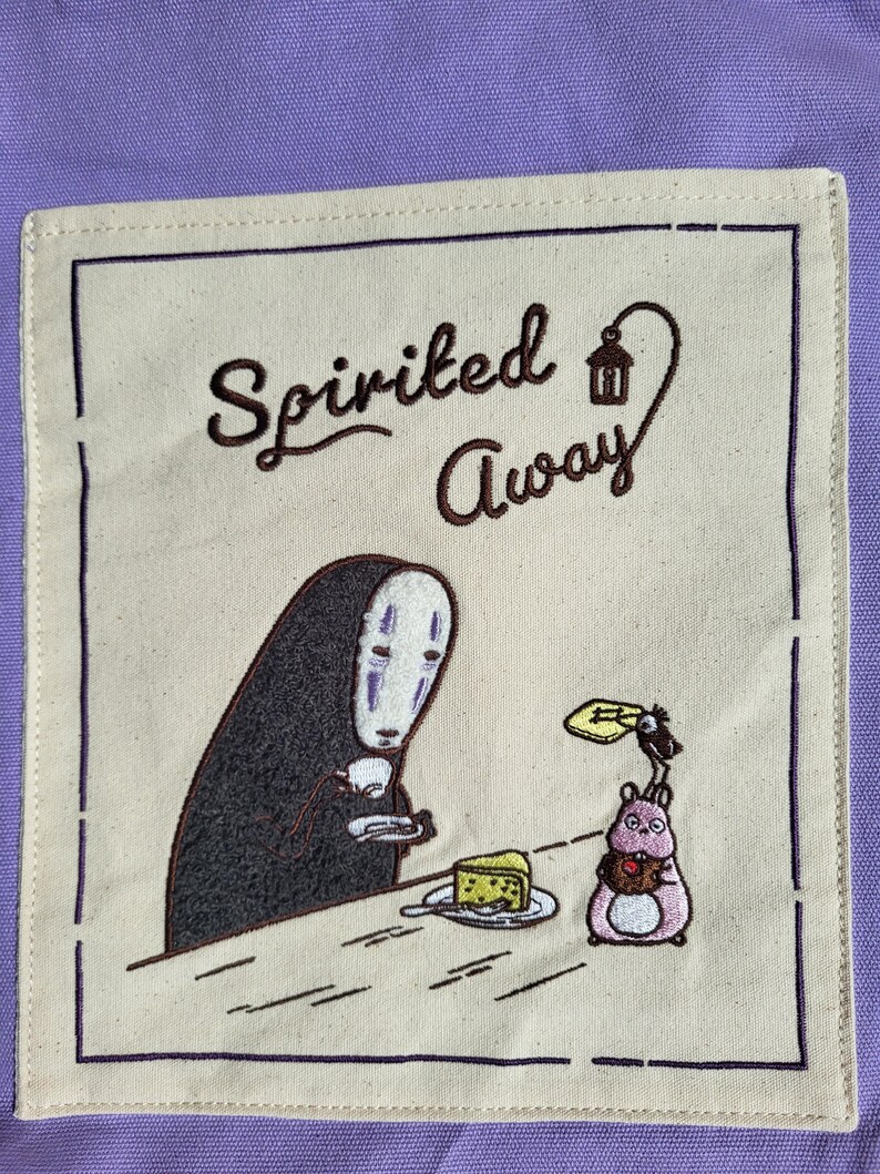 May include: A beige square patch with a dark purple border features an embroidered scene from "Spirited Away." The design includes the text "Spirited Away," a character with a white mask, and a pink creature holding a chocolate.