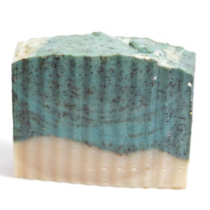 May include: A bar of handmade soap with a green and white swirl pattern. The soap has a speckled appearance and is made with natural ingredients.
