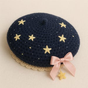 Può includere: Basco all'uncinetto blu navy con stelle gialle ricamate e piccoli puntini bianchi. Il basco ha un bordo beige smerlato e un fiocco di raso rosa con un ciondolo a forma di stella gialla. Un accessorio stravagante.