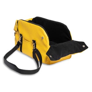 May include: A yellow pet carrier with a black strap and a black fleece lining. The carrier has a zipped opening and a handle.