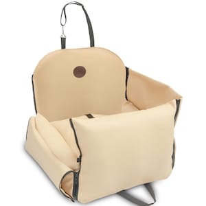 May include: Beige canvas dog car seat with a zippered opening and a black handle. The seat has a brown leather patch with a logo on the back.
