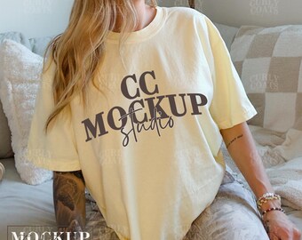 Könnte beinhalten: Eine Frau trägt ein hellgelbes T-Shirt mit dem Aufdruck "CC MOCKUP Studio" auf der Vorderseite. Das T-Shirt ist locker geschnitten und hat einen Rundhalsausschnitt.