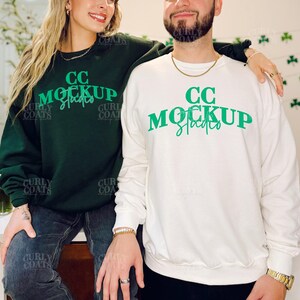 May include: A dark green sweatshirt and a white sweatshirt. Both sweatshirts have the text "CC Mockup Studios" in green. The sweatshirts are long-sleeved and appear to be made of a soft material.
