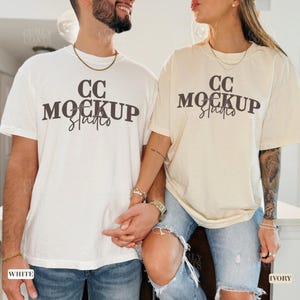 Pode incluir: Duas camisetas, uma branca e outra marfim, com o texto "CC Mockup Studio" impresso na frente. As camisetas estão sendo modeladas por duas pessoas.