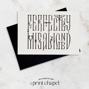 Op de afbeelding: Een witte kaart met de woorden "PERFECTLY MISALIGNED" in een decoratief zwart lettertype, op een zwarte envelop. De kaart bevat ook de tekst "ART & DESIGN BY HAND" en "©print chapel" in een kleiner lettertype.