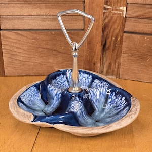 May include: A vintage ceramic serving dish with a blue and white swirl design. The dish has a silver handle and a light brown rim. The dish is divided into three sections, perfect for serving snacks or appetizers.