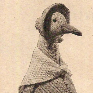 May include: A knitted penguin doll wearing a bonnet and a shawl. The doll is made of brown yarn and has a long, pointed beak.