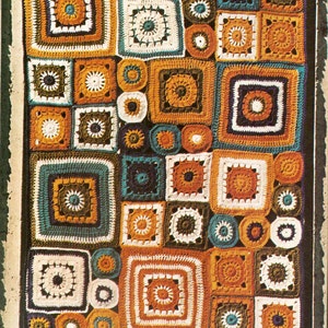 May include: A crocheted blanket with a patchwork design featuring squares and circles in shades of orange, brown, white, green, and blue. The blanket has a fringe border.