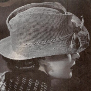 May include: A gray crocheted hat with a wide brim and a bow on the side.