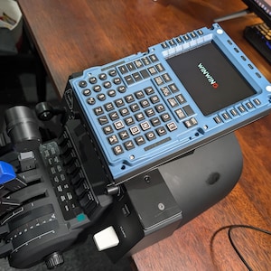 May include: A blue and black flight simulator control panel with a screen displaying the word "VINWIN" in white text. The panel has a keyboard with white keys and a joystick with red and blue buttons.