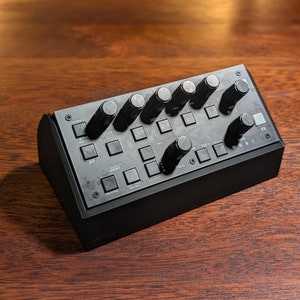 Peut inclure: Panneau de commande noir avec plusieurs boutons et molettes. Le panneau est étiqueté "VOR", "HDG", "NAV", "FREQ", "AP", "ATT", "X2", et "TO/SYNC".