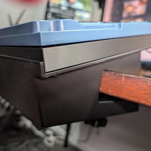 May include: A close-up view of a mechanical keyboard with a light blue top and a black base. The keyboard is mounted on a wooden desk. The keyboard's design is modern and sleek, with a focus on functionality and aesthetics.
