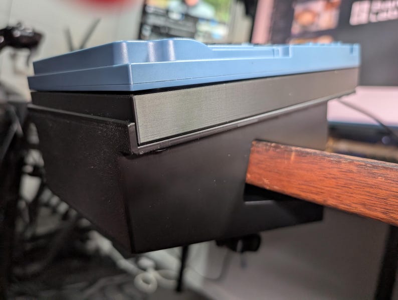 May include: A close-up view of a mechanical keyboard with a light blue top and a black base. The keyboard is mounted on a wooden desk. The keyboard's design is modern and sleek, with a focus on functionality and aesthetics.
