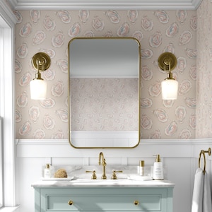 May include: A bathroom scene featuring a rectangular gold-framed mirror above a light blue vanity. The walls are adorned with oyster-patterned wallpaper in beige, pink, and blue. Two gold sconces with white glass shades flank the mirror, and gold fixtures complete the look.