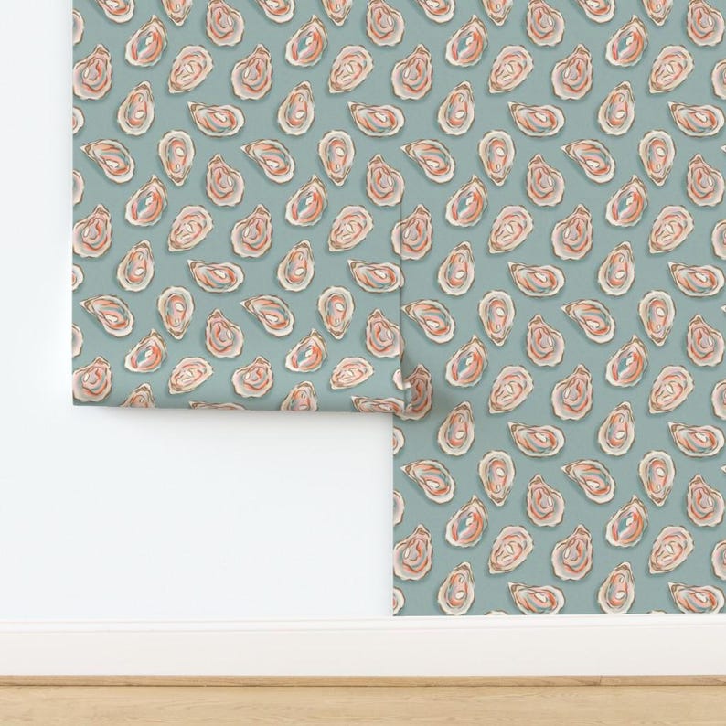 May include: Wallpaper featuring a repeating pattern of oyster shells in shades of pink, orange, and blue on a muted teal background. The design is a watercolor style, with each shell slightly different. The wallpaper is shown partially rolled out.