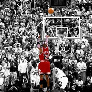 以下が含まれることがあります： バスケットボールの試合の白黒画像。背番号23の赤いユニフォームを着た選手がボールをゴールに向かってシュートしています。大勢の観客が試合を観戦しています。スコアボードには試合時間が表示されています。