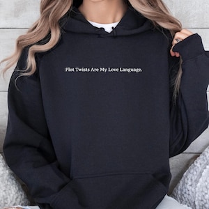 May include: A black hooded sweatshirt with the text "Plot Twists Are My Love Language." printed on the front.