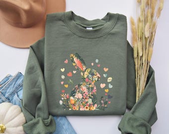 Può includere: Una felpa verde con un design di coniglio floreale. Il coniglio è fatto di fiori colorati e circondato da piccoli cuori.