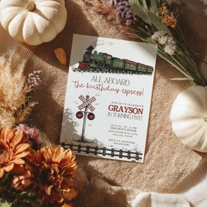 Könnte beinhalten: Eine Geburtstagseinladung mit einer Illustration eines grünen Zuges und dem Text "All Aboard the birthday express!". Die Einladung enthält Details für Graysons fünften Geburtstag, mit einem Bahnübergangsschild.
