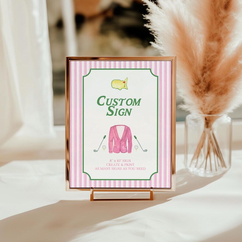 Puede incluir: Un letrero personalizado enmarcado con un borde a rayas rosas y blancas. El letrero presenta un dise&ntilde;o verde y blanco con las palabras "Custom Sign" y una ilustraci&oacute;n de acuarela de una chaqueta rosa, palos de golf y un logotipo de campo de golf. El letrero mide 20,3 x 25,4 cm.