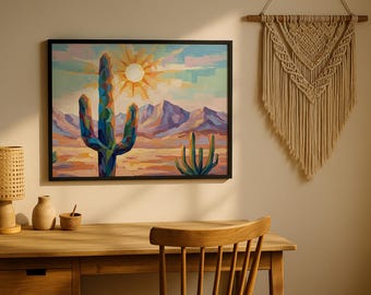May include: A framed desert landscape painting featuring a large cactus, mountains, and a setting sun. A woven lamp, small vase, and a macrame wall hanging are also visible.