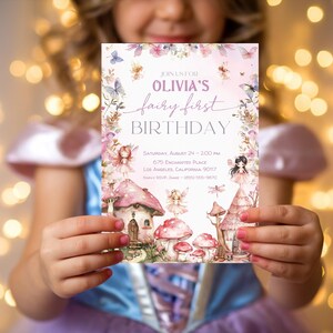May include: A pink and purple fairy-themed birthday party invitation with a watercolor illustration of a fairy house, mushrooms, and fairies. The text reads "Join us for Olivia's fairy first birthday. Saturday, August 24 - 2:00 pm, 675 Enchanted Place, Los Angeles, California 90117."