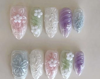 May include: Set of ten false nails with a variety of pastel colours and 3D flower designs. The nails are oval shaped and have a glossy finish.