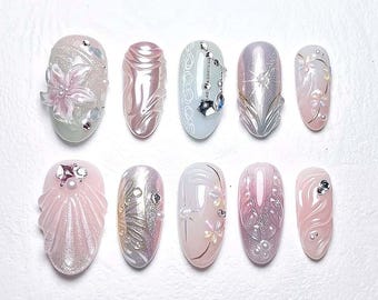 May include: Ten oval-shaped nail designs with a pearly white and pink base. The designs include flowers, swirls, and geometric patterns.