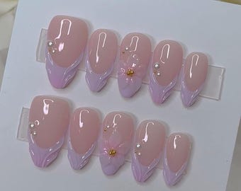 May include: Set of ten pink and white false nails with a floral design and pearl accents.