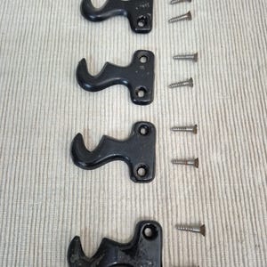 May include: Four black metal wall hooks, each featuring a curved design and two circular mounting holes. The set includes eight small silver-colored metal screws, with two screws positioned to the right of each individual hook for installation.